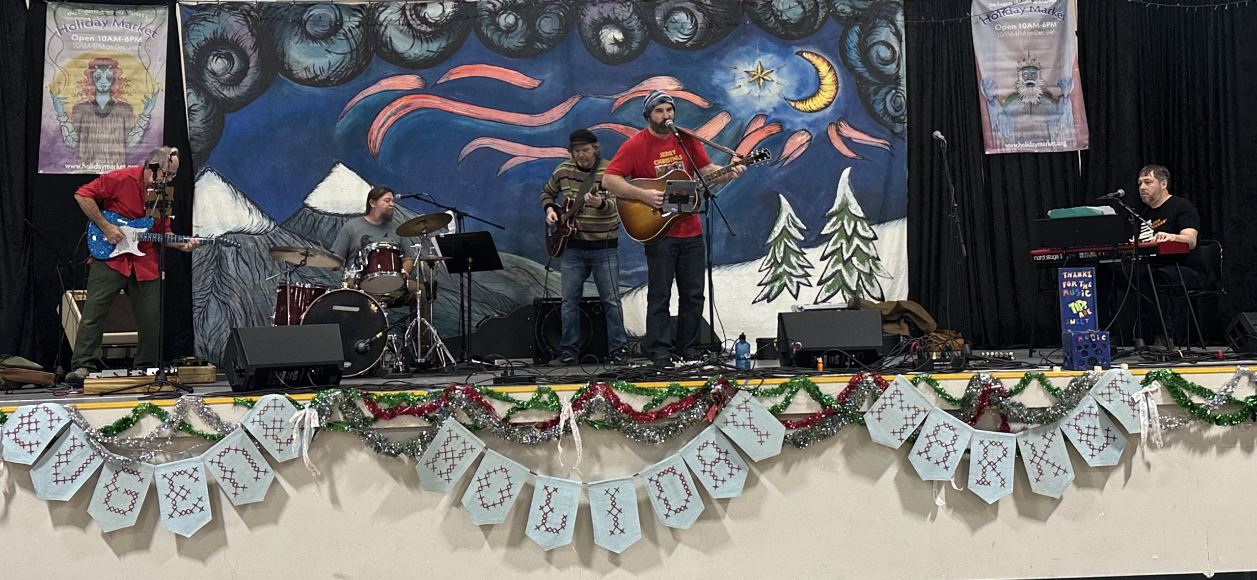 Musicians in the band Parker Galactic performing on stage at the Eugene Holiday Market.